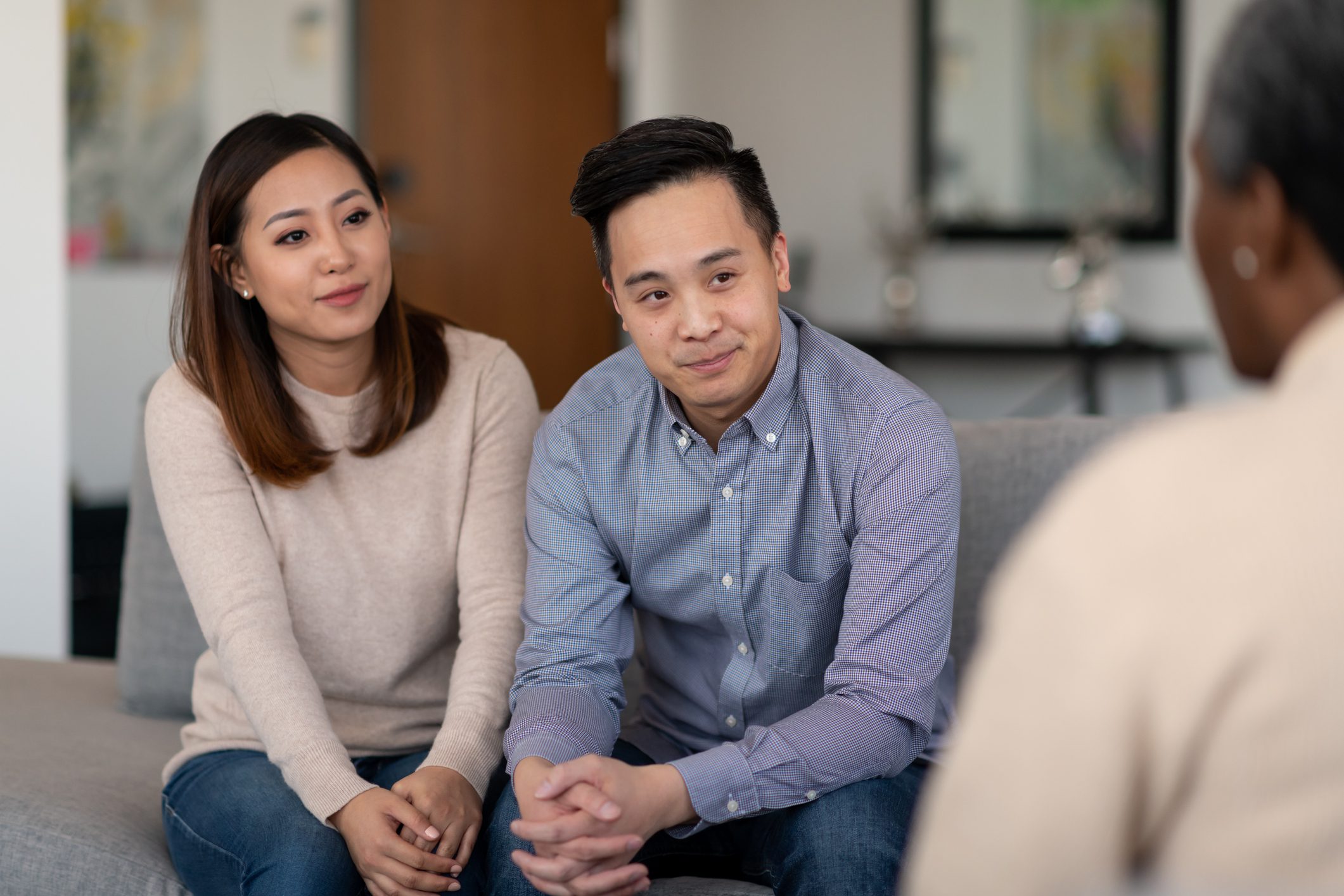 A married couple sits close to each each while listening to a therapist